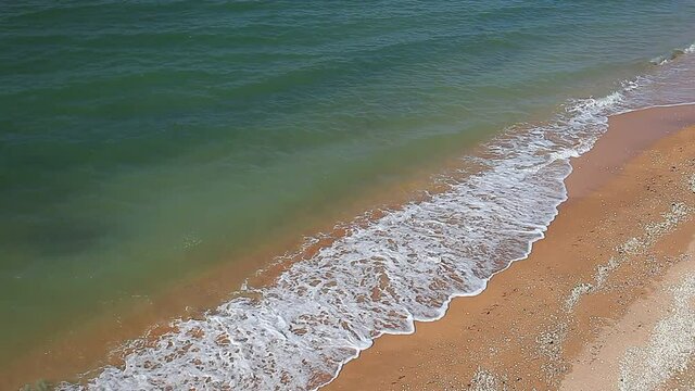 Sea surf, waves on waters, beach with yellow sand on coast.