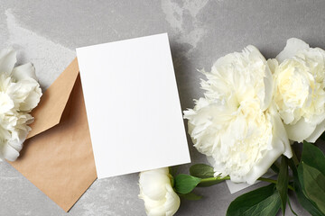 Obraz na płótnie Canvas Card mockup with copy space and white peony flowers and envelope on grey