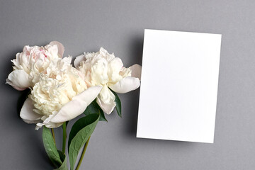 Greeting card mockup with copy space and white peony flowers on grey