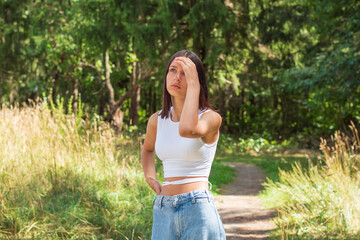 A teenage girl walks dreamily through a landscaped park on a beautiful sunny day.