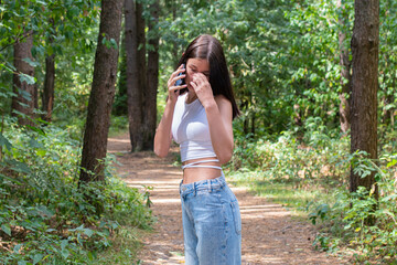 A teenage girl walks dreamily through a landscaped park on a beautiful sunny day.