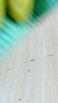 Human hand in yellow rubber gloves with blue rag with microfiber, carefully cleaning table from bread crumbs. Vertical video. Close-up.