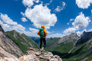 Naklejka na ściany i meble Successful woman backpacker hiking on sunset alpine mountain peak