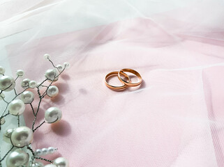 Flat lay background with a pair of gold rings and pearl necklace for wedding or engagement decorated with white lace of a veil of the bride,  with copy space. Love concept, top view, lay out. Banner
