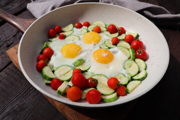 Late breakfast , fried eggs with zucchini, cherry tomaroes. Shakshuka in frying pan on rustic background. Arabic cuisine. Kosher food.