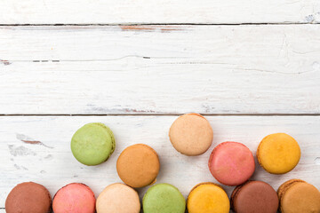Colorful border of French macarons pastry on rustic table flat lay top view