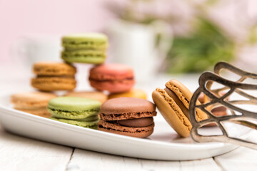 Variety of macarons on a plate with pastry tongs, shallow depth of field