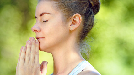 Concentrated young woman blonde meditates in yoga pose joining hands in namaste asana