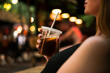 woman drinking a cocktail at a summer party in a restaurant close-up. woman holding cold drink with her