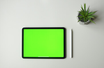 Green background mock-up on tablet device with stylus. Minimalism style top view