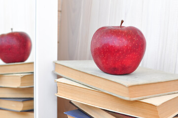old thick textbook and red apple  on the school desk , knowledge concept, study hard