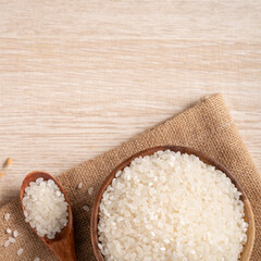 White rice in a bowl on wooden table background.