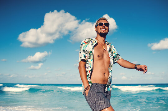 Attractive tourist man in hawaiian shirt smiling against sea or the ocean background. Travel vacation holiday. Man enjoy tropical season