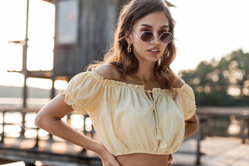 Summer portrait of a beautiful young woman in an elegant summer dress with fashion sunglasses walks outdoors