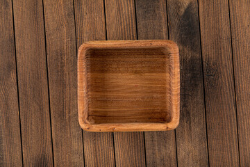 Square brown empty natural wooden bowl on a wooden background