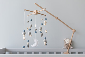 Baby crib mobile with stars, planets and moon. Kids handmade toys above the newborn crib. First baby eco-friendly toys made from felt and wood on gray background