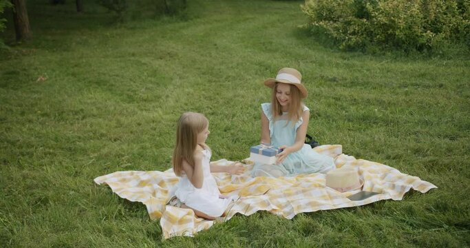 The younger sister gives a present to the older sister a photo insta camera