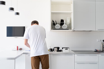 Man in white t shirt washing dishes in the kitchen