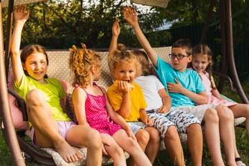 Fototapeta premium Children sitting on large swing in backyard