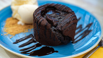 Summer cafe concept: vanilla ice cream with hot chocolate souffle or lava cake served on blue cake, light color wooden table