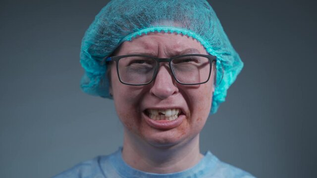 Portrait of woman patient in hospital in medical clothes after car accident received face injury and dental, looking at camera on gray background. Crying female victim of domestic violence and abuse.