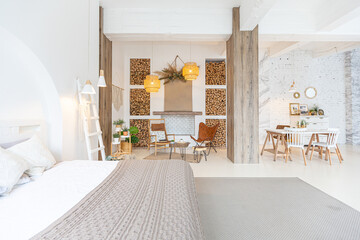 Fashionable modern interior of a light studio apartment with wooden columns in the loft style, decorated with brick, marble and wood with stylish furniture and white walls
