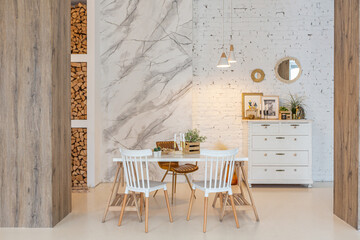 Fashionable modern interior of a light studio apartment with wooden columns in the loft style, decorated with brick, marble and wood with stylish furniture and white walls