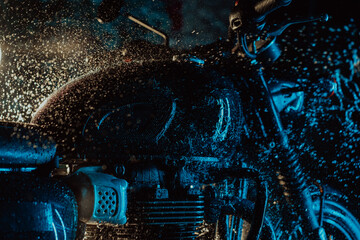 Retro styled motorcycle at wash under neon blue light. Washing with water details of classic black...