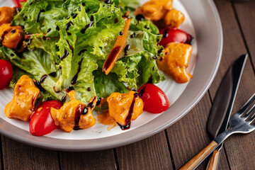 Salad with lettuce and fried chicken on wooden background