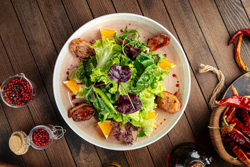 Salad with roasted duck greens and oranges mix on a wooden background