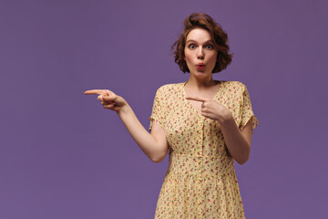 Lady in floral yellow dress posing isolated over violet background. Charming young girl with dark...