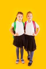 Two friendly schoolgirls in uniform are holding their hands on belt