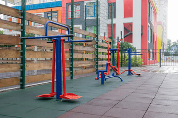 Exercise machines and fitness equipment for exercising on an open air sports ground in cloudy rainy weather without people.