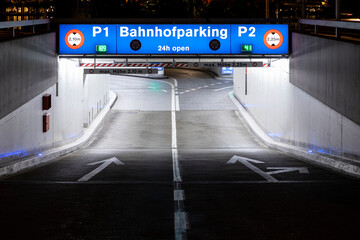 Underground car park entrance with german inscriptions in Luzern. Night view, illuminated by lights. Street signs on the ground.