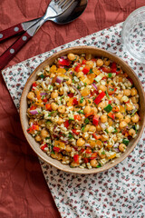Salad of bulgur, chickpeas and vegetables in a bowl close-up. Salad with chickpea, bulgur, tomato, pepper, cucumber, onion, parsley, and lemon juice. Vegan food, Middle Eastern food.