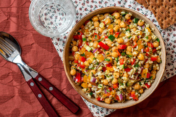 Salad of bulgur, chickpeas and vegetables in a bowl close-up. Salad with chickpea, bulgur, tomato, pepper, cucumber, onion, parsley, and lemon juice. Vegan food, Middle Eastern food.