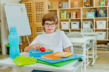 Elementary school student eating from the lunchbox in the classroom