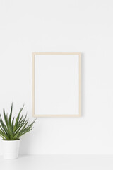Wooden frame mockup on the wall with a succulent plant.