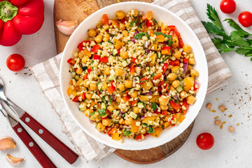 Salad of bulgur, chickpeas and vegetables in a bowl close-up. Salad with chickpea, bulgur, tomato, pepper, cucumber, onion, parsley, and lemon juice. Vegan food, Middle Eastern food.