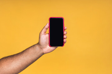 Black male african american indian hand touching mobile phone display and pointing with index finger at blank screen, isolated over yellow background, copy space, cutout.