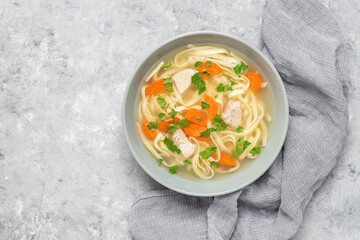 Chicken soup with homemade noodles on a gray concrete background. Top view, flat lay, copy space.