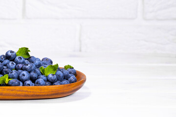 Blueberries With a Green Mint leaf in a Wooden Bowl on a white top view, Summer Freshly Berry, Copyspace