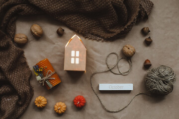 Fototapeta na wymiar Cozy autumn composition with paper house surrounded by autumn leaves, candles and pumpkin top view. Hygge home decor. Halloween and Thanksgiving concept