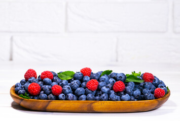 Blueberry and Raspberry With a Green Mint leaf in a Wooden Bowl on a white top view, Summer Freshly Berry, Copyspace