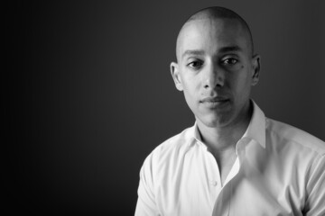Portrait of handsome bald businessman against gray background