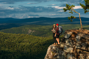A man and a woman in tourist equipment are standing on a rock and admiring the panoramic view. Two...