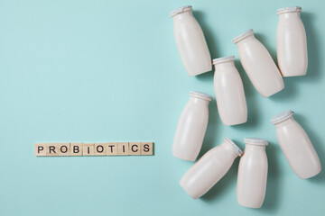 Bottles with probiotics and prebiotics dairy drink on light blue background.