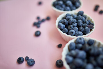 Flat lay of fresh organic juicy blueberries in a bowl on pink background