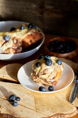 Cinnamon rolls with white chocolate and blueberries. Brioche. Side view, wooden background, icing sugar, cocoa, yeast buns.