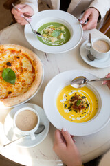 Women eating vegetarian cream soup and pizza